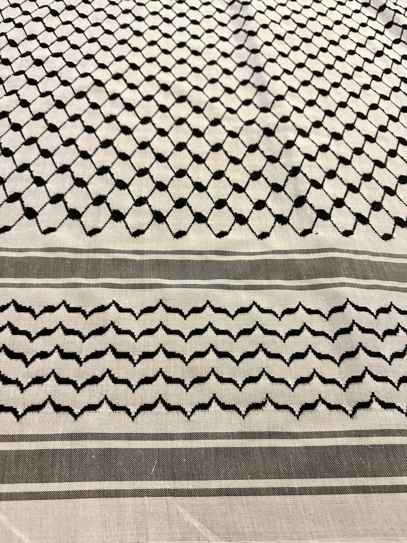 May include: A white and black patterned fabric with a geometric design. The fabric has a black and white striped border.