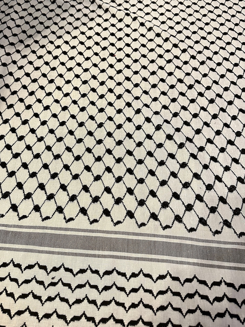 May include: White and black patterned fabric with a geometric design. The fabric has a black and white striped border.