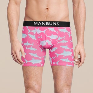 Könnte beinhalten: Rosa Boxershorts mit einem schwarzen Bund, auf dem "MANBUNS" steht, und einem weißen Hai-Muster.