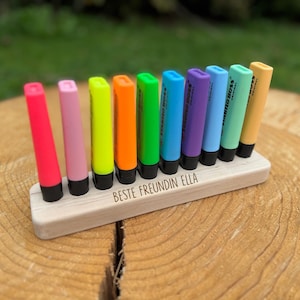 May include: A set of ten colorful highlighters in a wooden holder. The highlighters are in various colors, including pink, purple, green, and yellow. The wooden holder has the text "BESTE FREUNDIN ELLA" engraved on it.