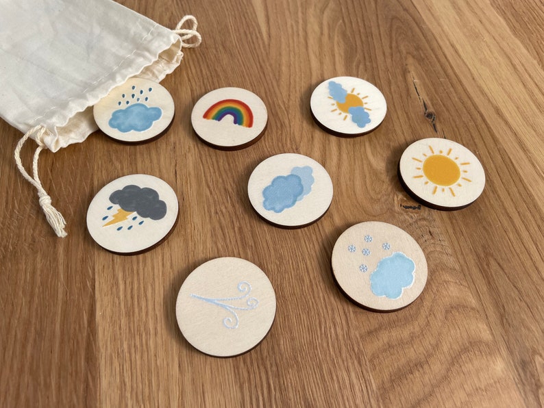 May include: Set of eight wooden weather themed circles with various weather icons including a rainbow, sun, clouds, rain, lightning, snow, and wind.