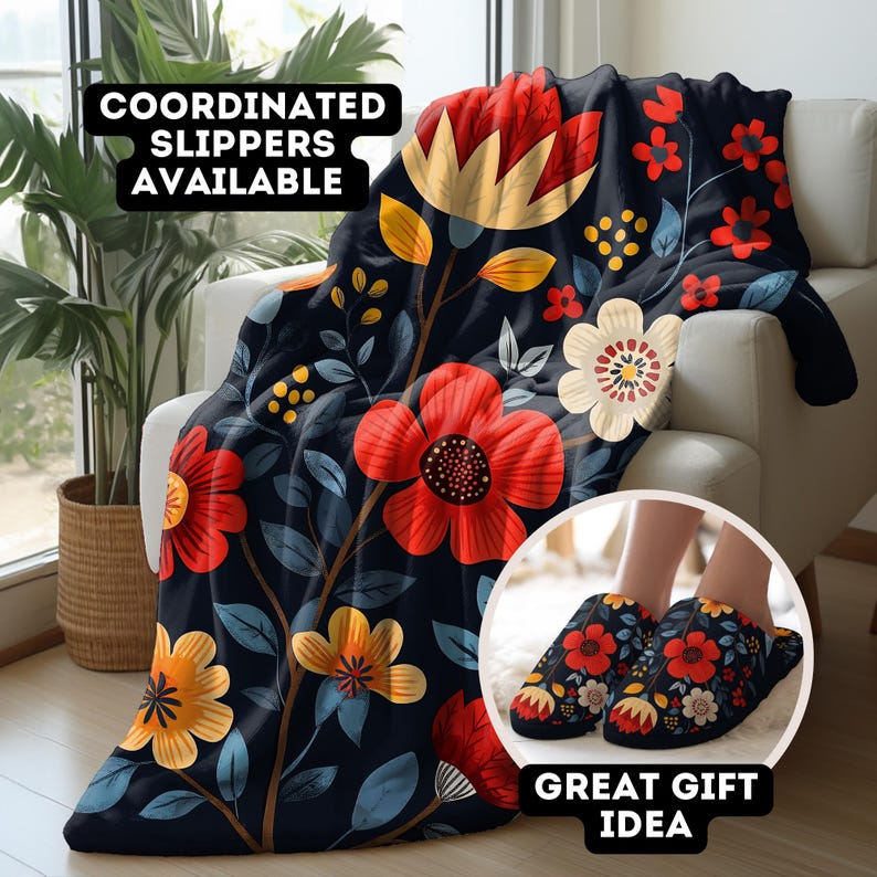 May include: A dark blue throw blanket with a floral pattern featuring red, yellow, and white flowers. The blanket is draped over a chair and there are matching slippers in the foreground. The text "COORDINATED SLIPPERS AVAILABLE" and "GREAT GIFT IDEA" are also visible.