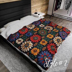 May include: A dark blue throw blanket with a colorful floral pattern. The pattern features red, yellow, orange, blue, and white flowers on a dark blue background.