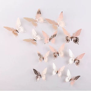May include: A set of 13 gold and white butterfly wall decals. The butterflies are arranged in a random pattern on a white background.