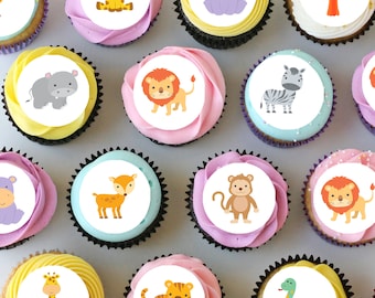 May include: Twelve cupcakes decorated with edible images of various animals, including a giraffe, a hippopotamus, a lion, a zebra, a deer, a monkey, a tiger, a snake, and a parrot. The cupcakes are arranged in a circle on a white surface.