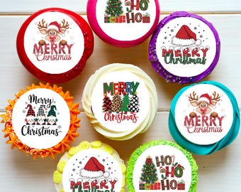 May include: A collection of decorated cupcakes with Christmas-themed designs. Each cupcake features a different design, including a reindeer, Santa hat, Christmas tree, and the words "Merry Christmas" and "Ho Ho Ho". The cupcakes are on a white surface.