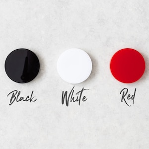 May include: Three round discs, one black, one white, and one red, with the words "Black", "White", and "Red" written below each disc.
