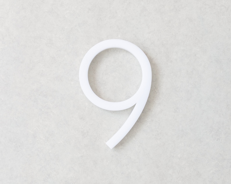 May include: White plastic number nine. The number is three-dimensional and has a rounded shape.