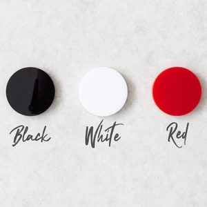K&ouml;nnte beinhalten: Drei runde Scheiben, eine schwarze, eine wei&szlig;e und eine rote, mit den W&ouml;rtern "Schwarz", "Wei&szlig;" und "Rot" unter jeder Scheibe.