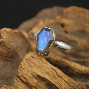 K&ouml;nnte beinhalten: Ein silberner Ring mit einem blauen Labradorit-Edelstein in Sargform.