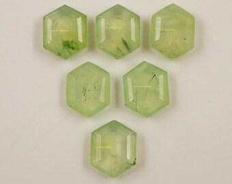 Könnte beinhalten: Sechs grüne Edelstein-Cabochons in sechseckiger Form. Die Steine haben eine durchscheinende Optik mit einer hellgrünen Farbe und weißen Einschlüssen.