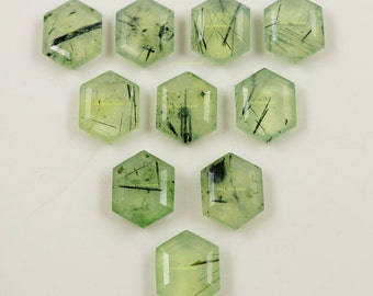Könnte beinhalten: Zehn hexagonale grüne Edelsteinkabochons mit schwarzen Einschlüssen. Die Cabochons sind facettiert und haben eine glatte, polierte Oberfläche.