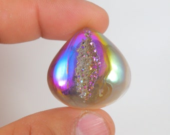 May include: A teardrop-shaped iridescent crystal with a clear, sparkly center. The crystal is a light gold color with a rainbow sheen.