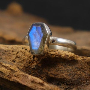 K&ouml;nnte beinhalten: Ein silberner Ring mit einem blauen Labradorit-Edelstein, der in einer Sargformfassung gefasst ist.