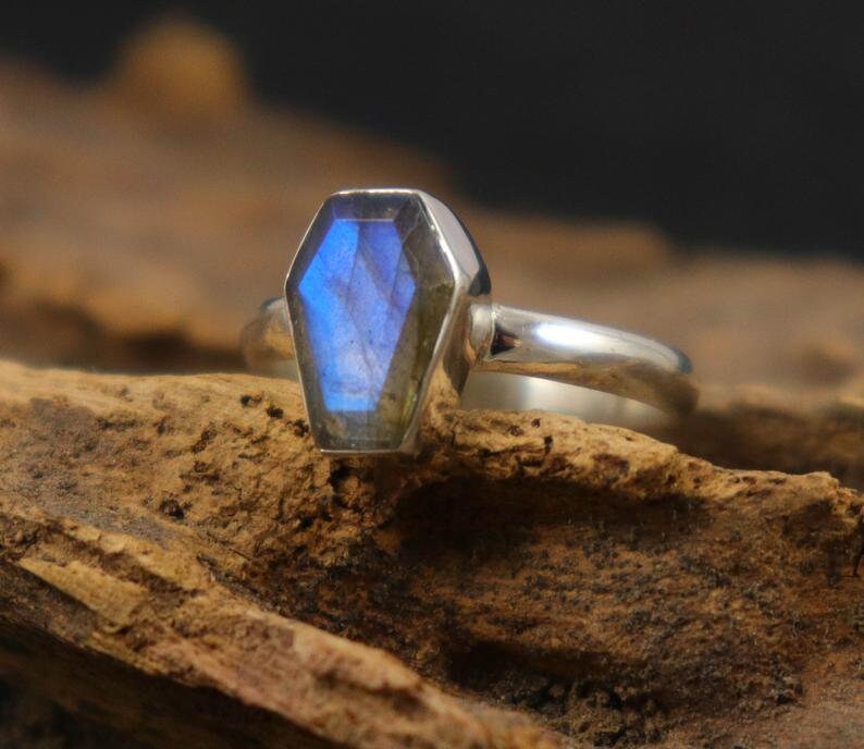 K&ouml;nnte beinhalten: Ein silberner Ring mit einem blauen Labradorit-Edelstein, der in einer Sargformfassung gefasst ist.