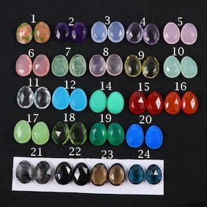 Peut inclure: Vingt-quatre paires de cabochons de pierres précieuses, numérotées de 1 à 24, disposées en quatre rangées de six paires. Les cabochons sont de différentes couleurs, notamment rose, vert, bleu, rouge et transparent.