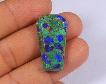 May include: A rectangular gemstone with a coffin shape. The stone features a mosaic of blue, green, and gold colors. The gemstone is held in a hand.