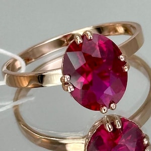 Op de afbeelding: Een ring van roségoud met een grote, gefacetteerde robijn. De ring is gezet met kleine klauwen rond de steen.
