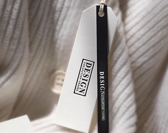 Pode incluir: Uma etiqueta de roupa branca com texto preto que diz "DESIGN COLLECTION VOGUE" e uma fita preta anexada.