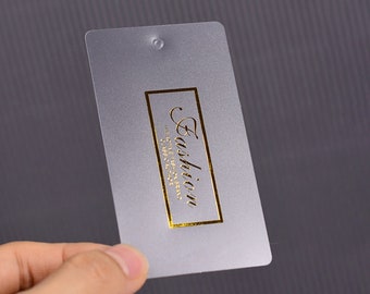 May include: A frosted plastic tag with a gold foil rectangle containing the text "Fashion" and the words "The style you deserve" in smaller font.