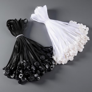May include: Two bundles of elastic cords with attached buttons. One bundle is black, and the other is white. The cords are tied together with a thin, clear band. The buttons are round and have a snap closure.