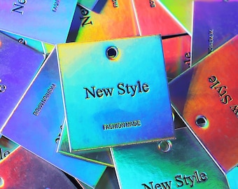 May include: A close-up of a pile of iridescent holographic tags with the text "New Style" and "Fashion Made" printed on them. The tags are square shaped and have a hole punched in the top corner.