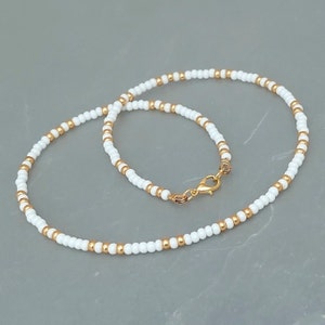 Peut inclure: Un collier de perles blanches et dor&eacute;es avec un fermoir dor&eacute;.