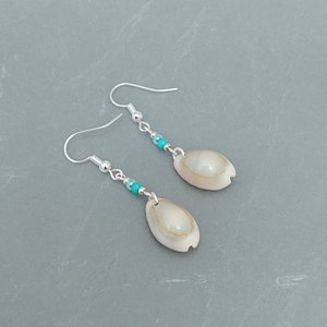 May include: A pair of silver earrings with turquoise beads and a white shell pendant.