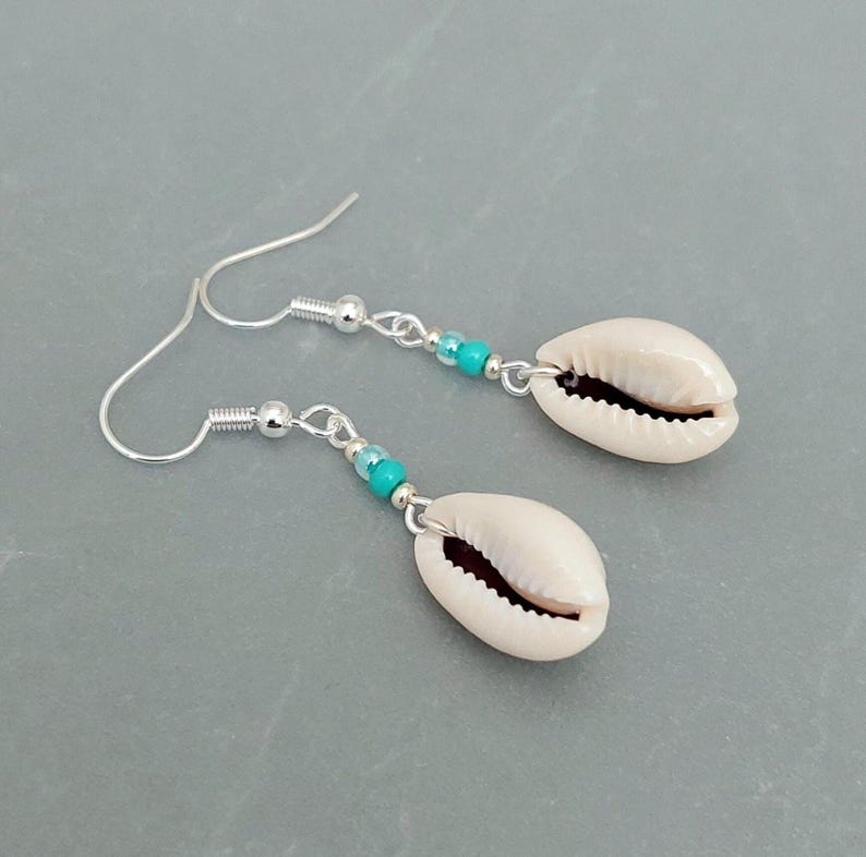 May include: A pair of silver earrings with white cowrie shells and turquoise beads.