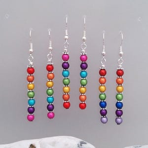 May include: Rainbow coloured beaded dangle earrings with silver hooks. Each earring has seven beads in a rainbow colour sequence.
