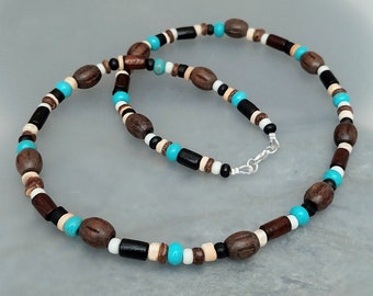 May include: A beaded necklace featuring a repeating pattern of brown oval wooden beads, cylindrical black beads, small turquoise round beads, and tiny white and tan spacer beads, finished with a silver-toned metal lobster claw clasp.