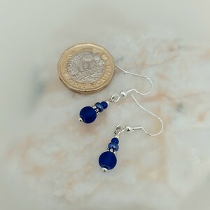 May include: A pair of silver dangle earrings with a dark blue glass bead and silver spacer beads.
