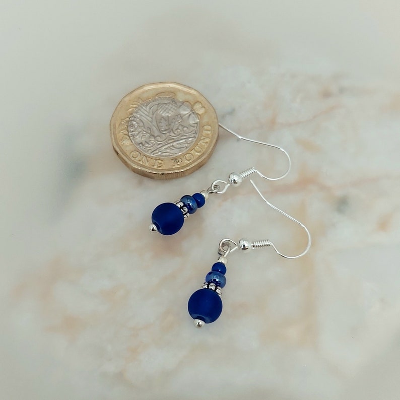 May include: A pair of silver dangle earrings with a dark blue glass bead and silver spacer beads.