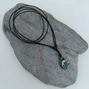 May include: A black leather cord necklace with a teardrop-shaped abalone shell pendant. The shell has iridescent green, blue, and gold colors.
