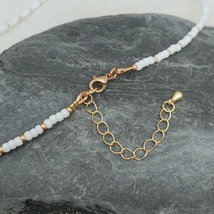 Peut inclure: Un collier de perles blanches avec un fermoir et une cha&icirc;ne d'extension dor&eacute;s.
