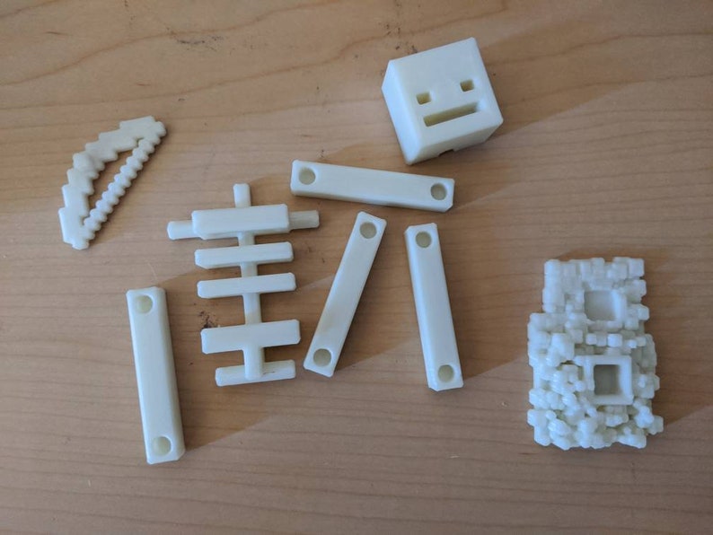 Puede incluir: Un conjunto de bloques de construcci&oacute;n de pl&aacute;stico blanco, que incluye un bloque cuadrado con una cara, un bloque curvo, un bloque con un patr&oacute;n de cuadr&iacute;cula y un bloque con una textura rugosa.