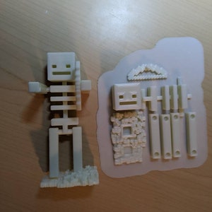 Puede incluir: Un modelo de esqueleto de pl&aacute;stico blanco impreso en 3D con una espada. El modelo est&aacute; ensamblado y listo para jugar. El modelo est&aacute; sobre una superficie de madera.