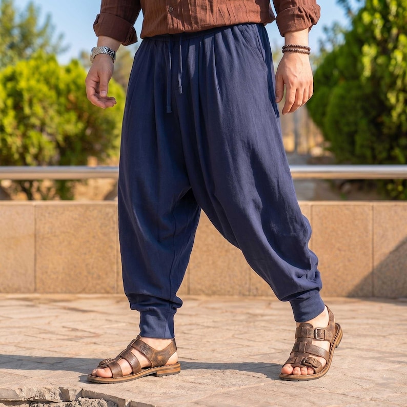 K&ouml;nnte beinhalten: Weit geschnittene, marineblaue Hose mit tiefem Schritt, elastischem Bund mit Kordelzug und eng zulaufenden Beinabschl&uuml;ssen. Die Hose zeichnet sich durch eine lockere Silhouette und einen einfarbigen Stoff mit matter Textur aus.