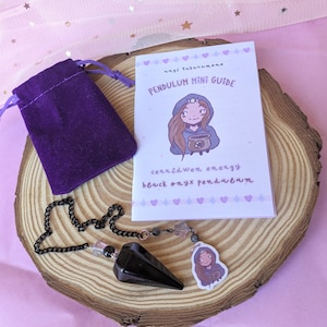 Puede incluir: Pendulo de ónix negro con una cadena negra y una bolsa de terciopelo morado. El péndulo viene con una mini guía con el texto "angie tsukamoto PENDULUM MINI GUIDE cerridwen energy black onyx pendulum".