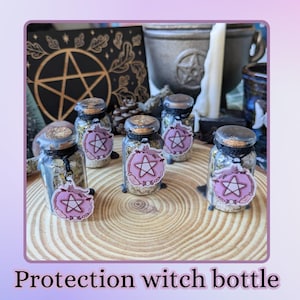 Peut inclure: Six petits flacons en verre avec des couvercles en liège, remplis d'herbes et ornés de breloques pentacle roses. Les flacons sont disposés sur une surface en bois, avec un symbole de pentagramme en arrière-plan. Le texte "Protection witch bottle" est en bas.