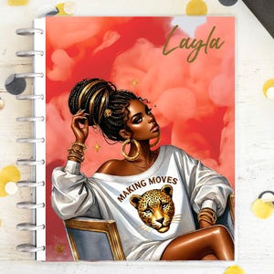 Può includere: Un'agenda con una copertina con l'illustrazione di una donna dalla pelle scura, con gioielli d'oro e una maglietta bianca con le parole "MAKING MOVES" e una faccia di leopardo. Lo sfondo è rosso con il nome "Layla" in oro.