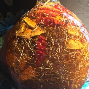 May include: A clear glass bottle filled with a golden liquid, containing dried red peppers, orange peels, and herbs.