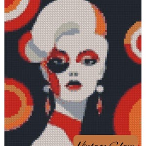 May include: A cross-stitch portrait of a woman in a retro style. The artwork features a white face with red lips and eye makeup, a black eye patch, and red accents. The background is dark with orange and red circular designs. The text "Vintage Glam" is at the bottom.