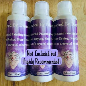 May include: Three white bottles with purple labels. The labels read "Diamond Painting Sealer" and include an illustration of a woman. Each bottle contains 250ml of product. The text "Not Included but Highly Recommended!" is also present.