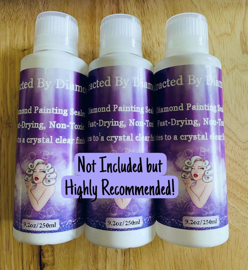 May include: Three white bottles with purple labels. The labels read "Diamond Painting Sealer" and include an illustration of a woman. Each bottle contains 250ml of product. The text "Not Included but Highly Recommended!" is also present.