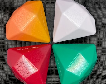 May include: Four diamond-shaped toys in orange, white, red, and green. The toys are made of a textured plastic.