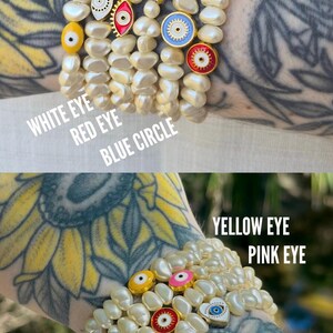May include: Pearl bracelets with decorative charms. The charms include a blue star, red circle, white eye, red eye, blue circle, yellow eye, pink eye, and white heart. The bracelets are worn on the wrist.