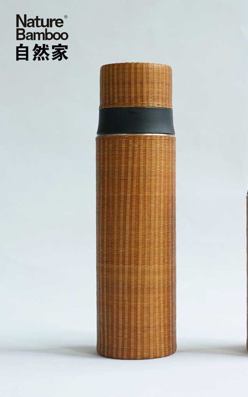 Puede incluir: Una botella de agua aislada de bamb&uacute; marr&oacute;n con una tapa negra y una banda plateada. La botella tiene el texto "Nature Bamboo 自然家" impreso en ella.