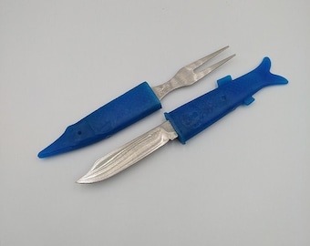 May include: A blue plastic handled knife and fork set with a fish design. The knife has a stainless steel blade and the fork has two tines.