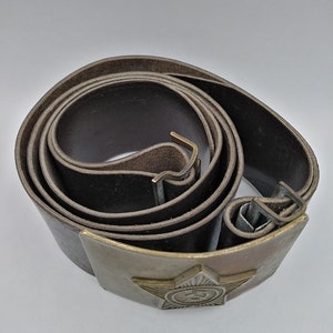 May include: A brown leather belt with a metal buckle featuring a five-pointed star and a hammer and sickle emblem.